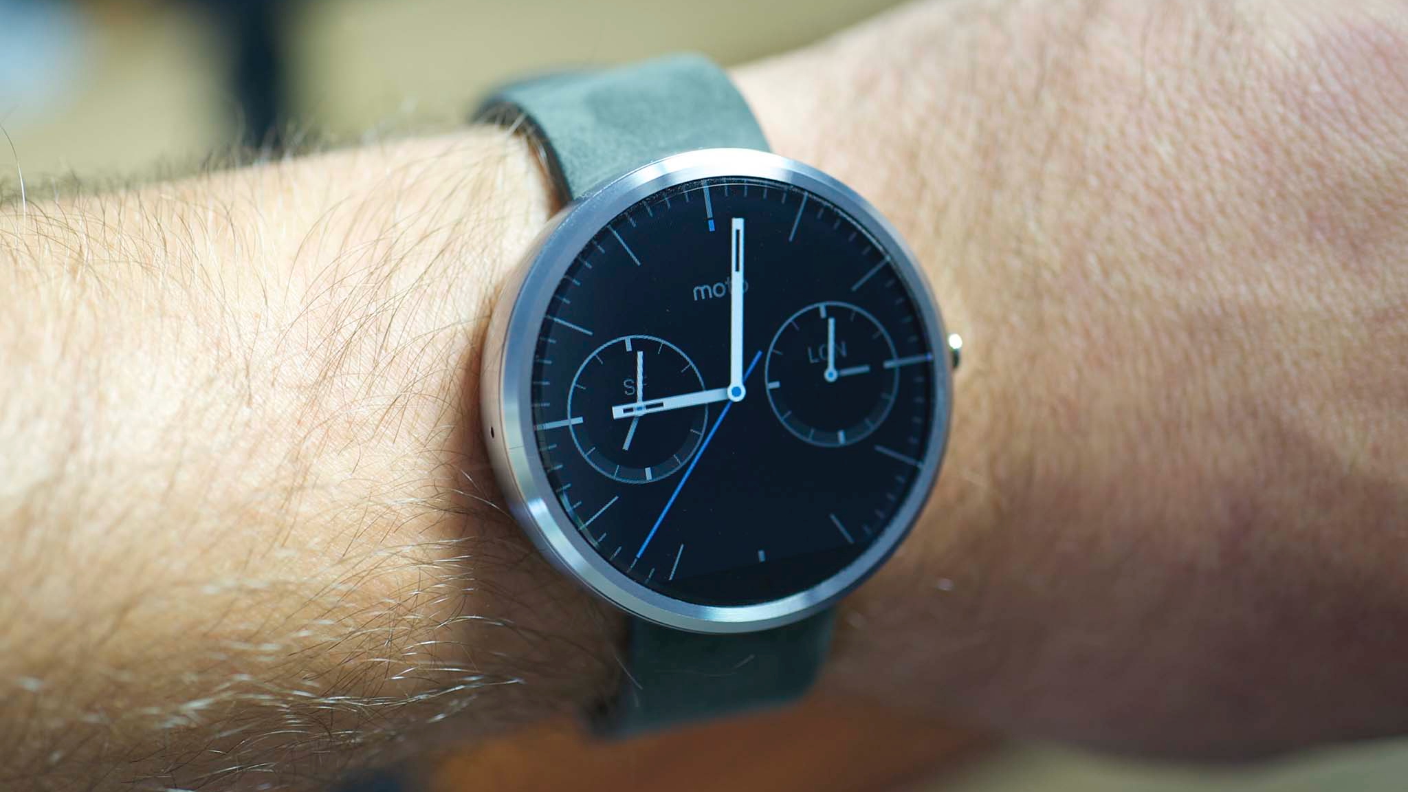 The Moto 360 smartwatch worn on a wrist, showing an analog watch face.